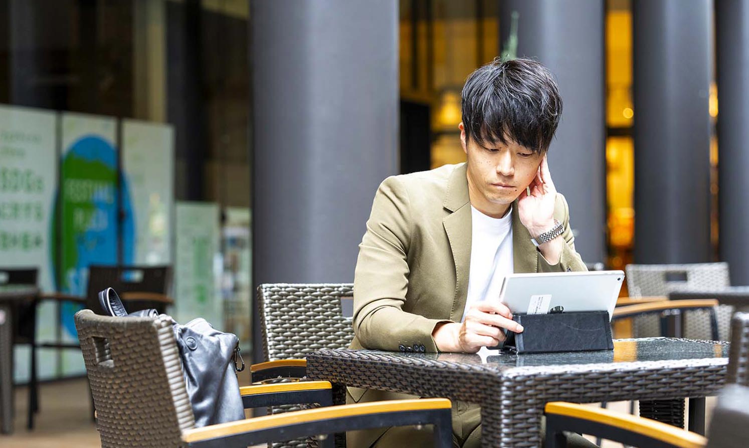 森下 大樹 テラス席でタブレット端末を見ている
